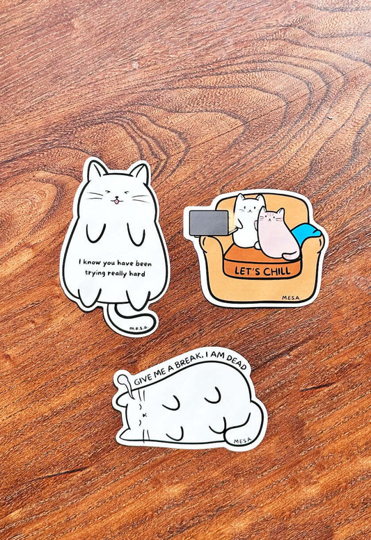 Cute cat sticker trio featuring motivational and relaxing messages from the Cozy Cat Collection on a wooden background.